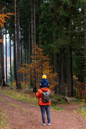 mother and son walk through the forest in autumn