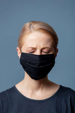 Woman in black face mask with headache on gray backgroundの写真素材
