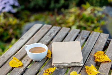Cup of coffee and a book on wooden table in gardenの写真素材