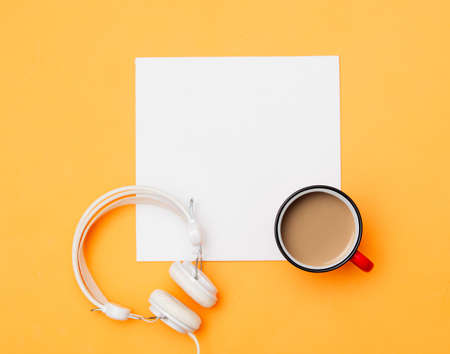 White mockup board and cup of coffee with headphones on yellow background