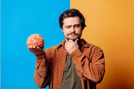 Guy in shirt hold human brain on yellow and blue backgroundsの写真素材