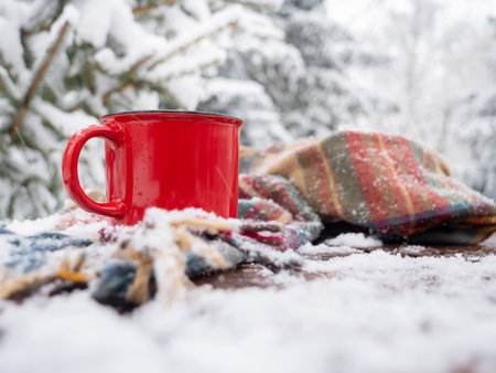 Red cup of coffee and scarf on wooden table in blizzardの写真素材