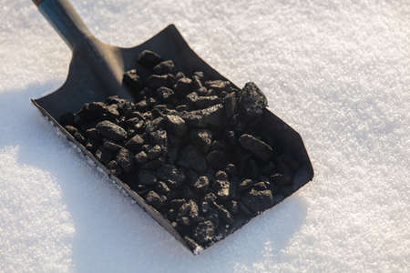 Shovel full of coal in the snow in winterの写真素材