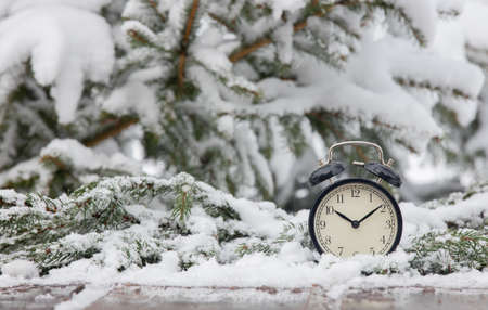 vintage alarm clock on wooden table in blizzardの写真素材