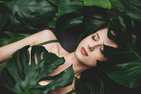 Beautiful white woman with palm leaves around