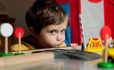 Little toddler boy play in trains at home. Close-up view