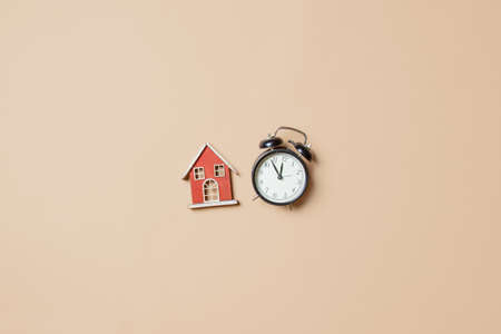 Little toy house and alarm clock on stark white background. Above viewの写真素材