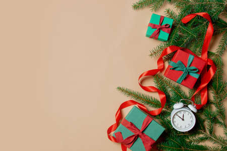 Holiday gift boxes with spruce branches and alarm clock on stark white color background. Above view