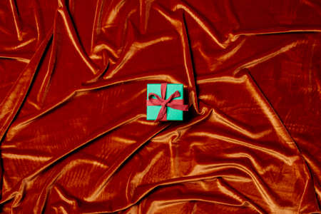 Holiday gift box on Crimson Red color fabric background. Above view.