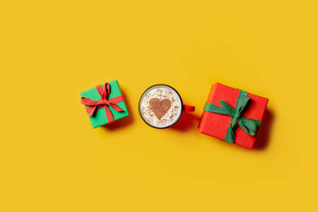 Holiday gifts and cup of coffee with heart shape on yellow background. Top viewの写真素材