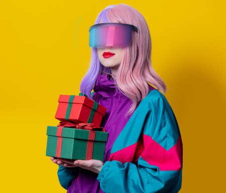 Style woman in VR glasses and 90s sport suit hold gift box on yellow background