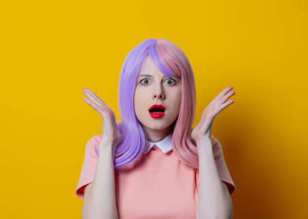 Girl with purple hair and pink dress on yellow backgroundの写真素材