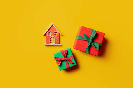 Two holiday gift boxes and toy house on yellow background. Top viewの写真素材