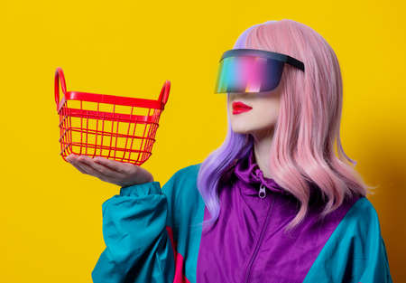 Girl with purple hair and red sweater hold black shopping cart on blue backgroundの写真素材