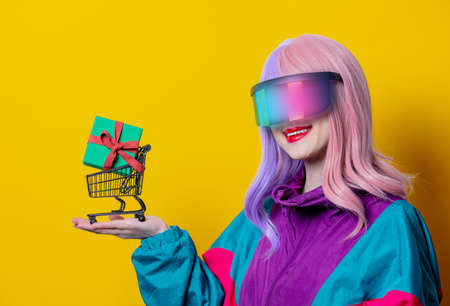 Girl with purple hair and red sweater hold black shopping cart on blue backgroundの写真素材
