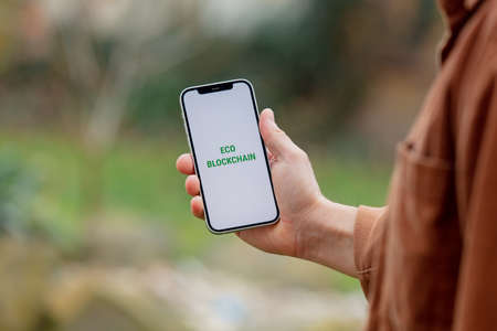 23 nov 2021 - Wroclaw, Poland: Man hold iPhone with green eco blockchain text. Trend of 2022 yearのeditorial素材
