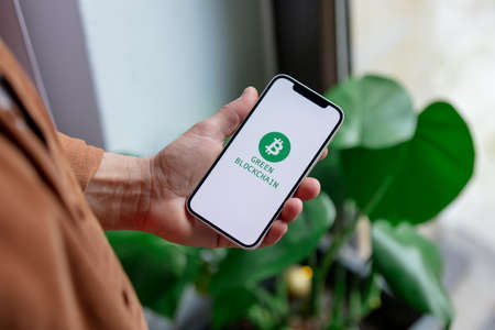 23 nov 2021 - Wroclaw, Poland: Man hold iPhone with green eco bitcoin logo and blockchain text. Trend of 2022 yearのeditorial素材