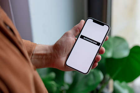 23 nov 2021 - Wroclaw, Poland: Man hold iPhone with blockchain spam text. Trend of 2022 yearのeditorial素材