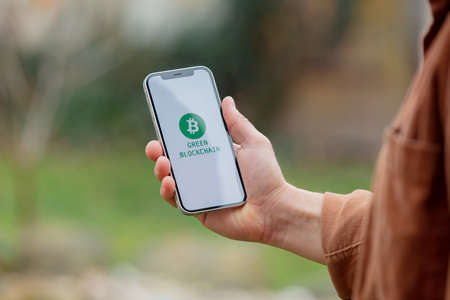 23 nov 2021 - Wroclaw, Poland: Man hold iPhone with green eco bitcoin logo and blockchain text. Trend of 2022 yearのeditorial素材