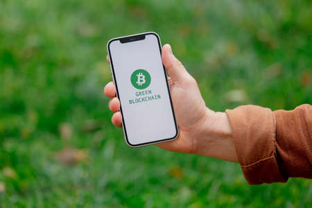 23 nov 2021 - Wroclaw, Poland: Man hold iPhone with green eco bitcoin logo and blockchain text. Trend of 2022 yearのeditorial素材