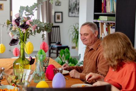 Grandpa and grandma eating at Easter dinner sitting at the table at homeの写真素材