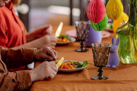 Grandpa and grandma eating at Easter dinner sitting at the table at homeの写真素材