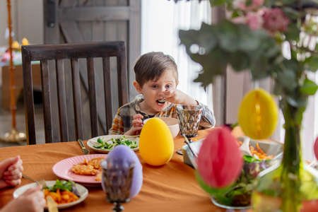 Little boy eating at Easter dinner table at homeの写真素材