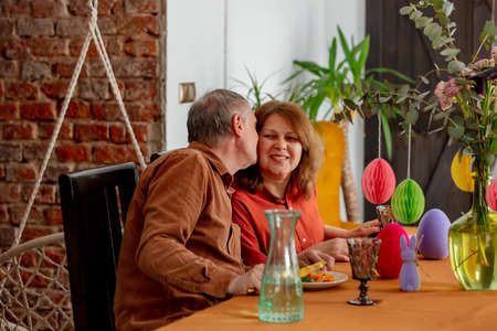 Grandpa and grandma eating at Easter dinner sitting at the table at homeの写真素材