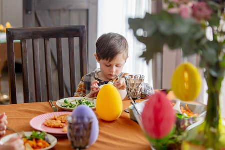 Little boy eating an ice cream at Easter dinner table at homeの写真素材