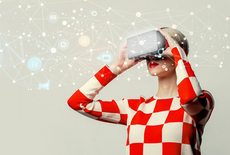 Beautiful woman with blond hair in a 70s red square dress with VR glassesの写真素材