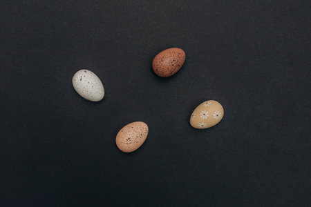 Decorative Easter eggs on a black background, top view, concept of festive holiday decorの写真素材