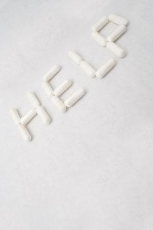 Closeup of "HELP" text written with capsules on white paperの写真素材