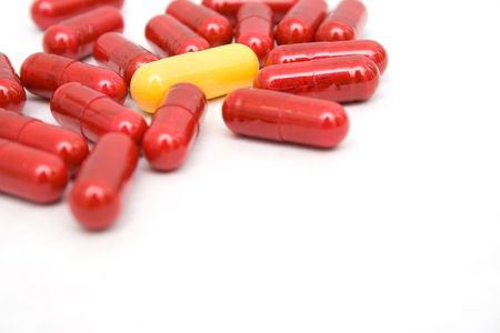 Group of capsules on white background - main focus on the yellow capsule