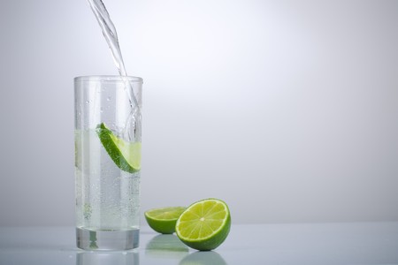 Filling a glass of water with limesの写真素材