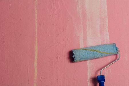 Paint roller leaning against the pink wall, with a white brushstroke on the rightの写真素材