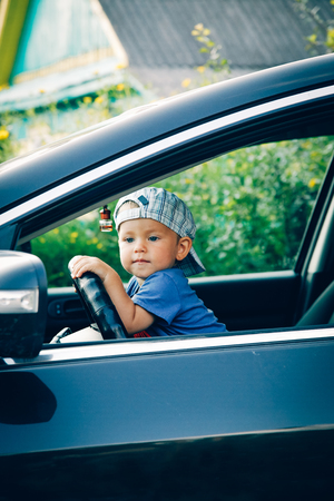 Little boy driving a car looking out the windowの写真素材