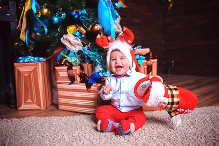 The child is happy on a festive day near the Christmas treeの写真素材
