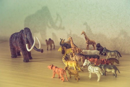 Wild animals against a huge prehistoric mammothの写真素材