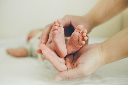 Mom gently massaging the tiny feet of a babyの写真素材