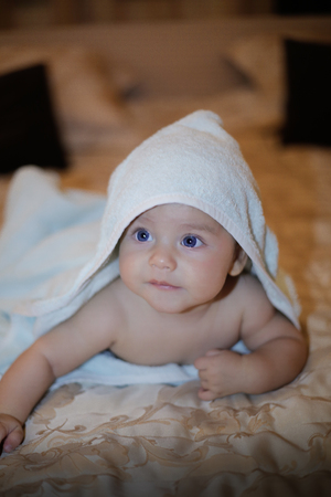 Happy baby wrapped in a towel after a bathの写真素材