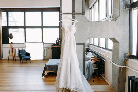 Beautiful women wedding dress weighs on the hangers in the big hall on the wallの写真素材