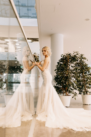 Elegant bride in a white dress standing on the stairs with a wedding bouquetの写真素材