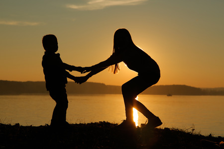 Children at sunset on the beach holding handsの写真素材