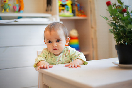 Small child sitting at a white table in kindergarten