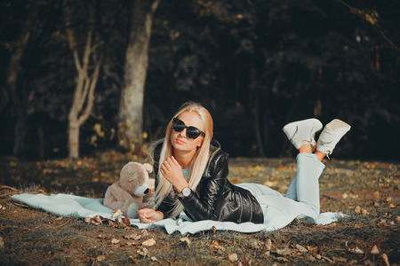 Blonde girl in black glasses lying on a blanket in the Parkの写真素材