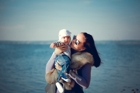 Beautiful mother with a baby resting by the blue seaの写真素材