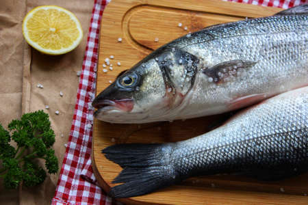 Raw fish on a cutting Board decorated with a slice of lemon close up