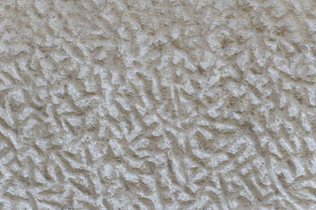 A solid wall of rough gray cement with irregular indentations