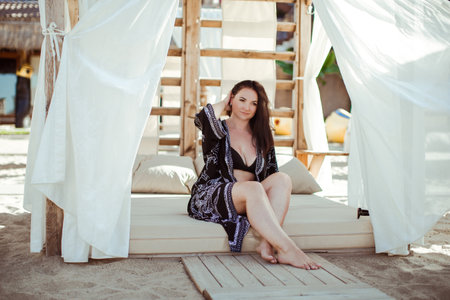 A girl in a black robe is sitting in a beach tent