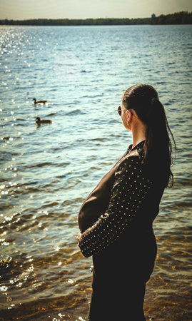 Pregnant girl with glasses on the background of the seaの写真素材